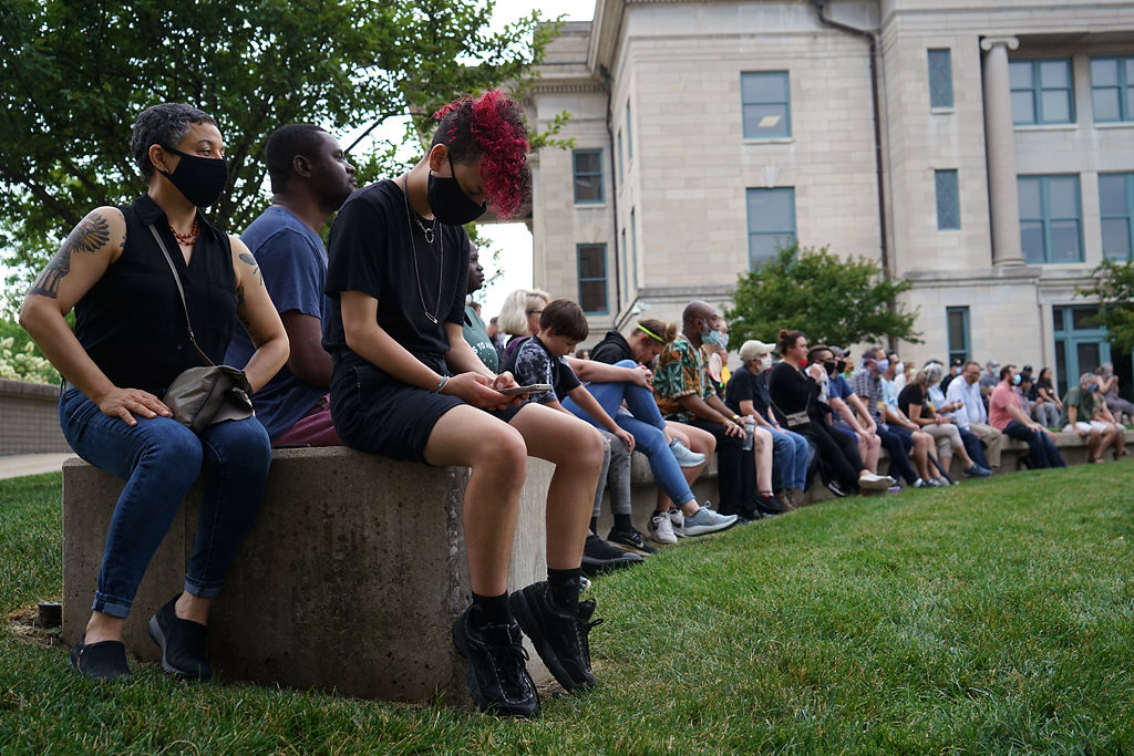 People sit at the Boone County Courthouse plaza and listen to speech on Friday